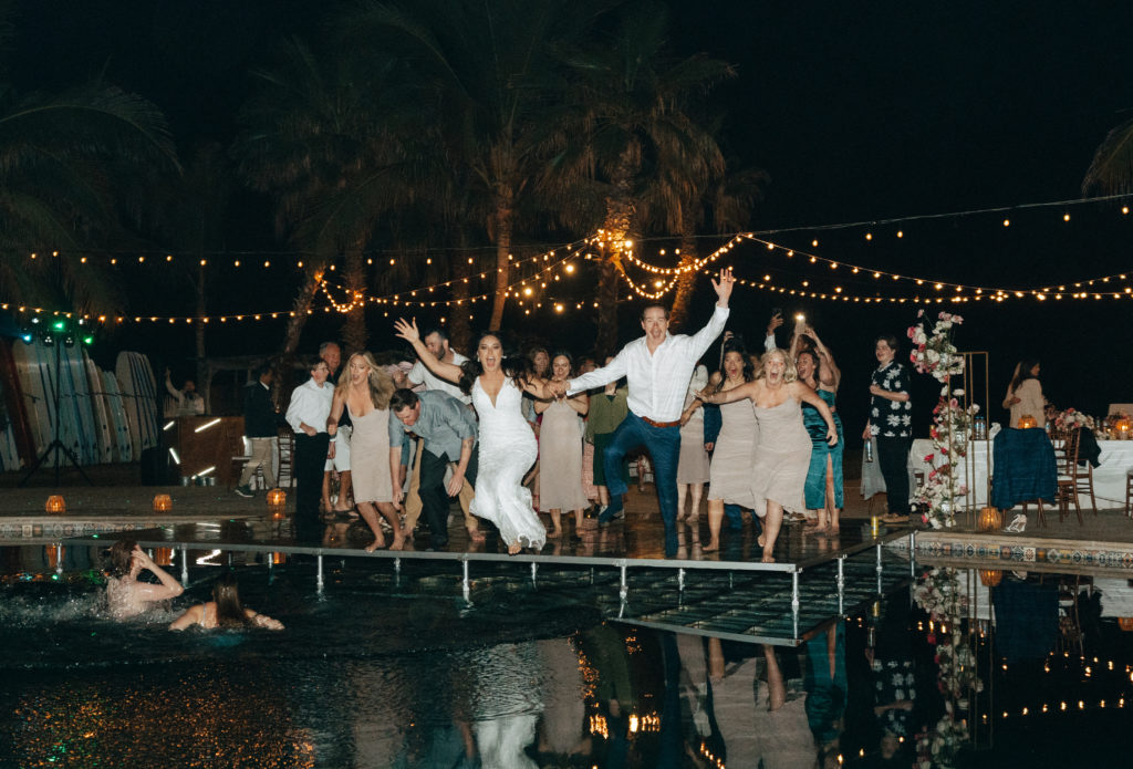 bride and groom jumping into pool on wedding day