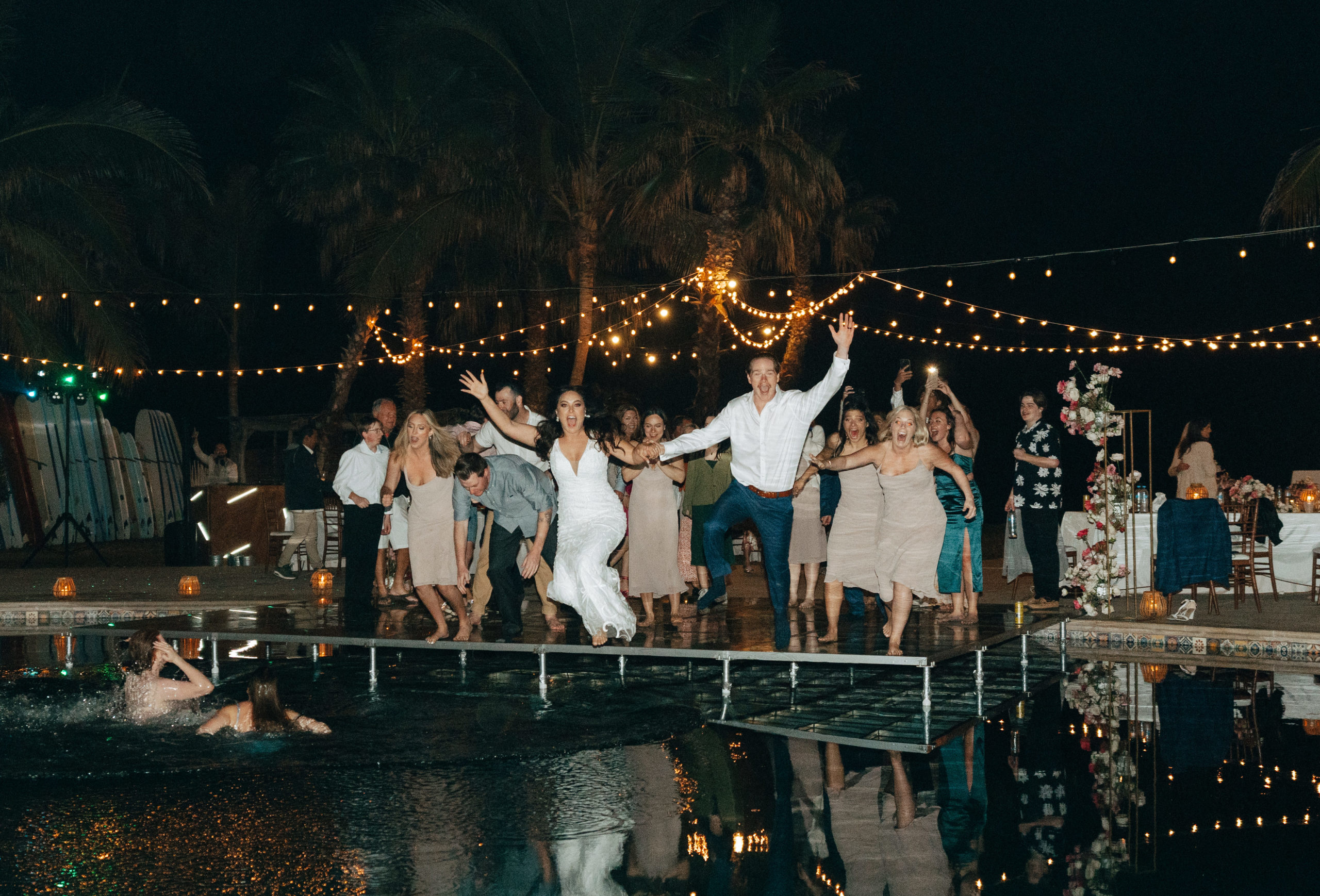 bride and groom jumping in pool