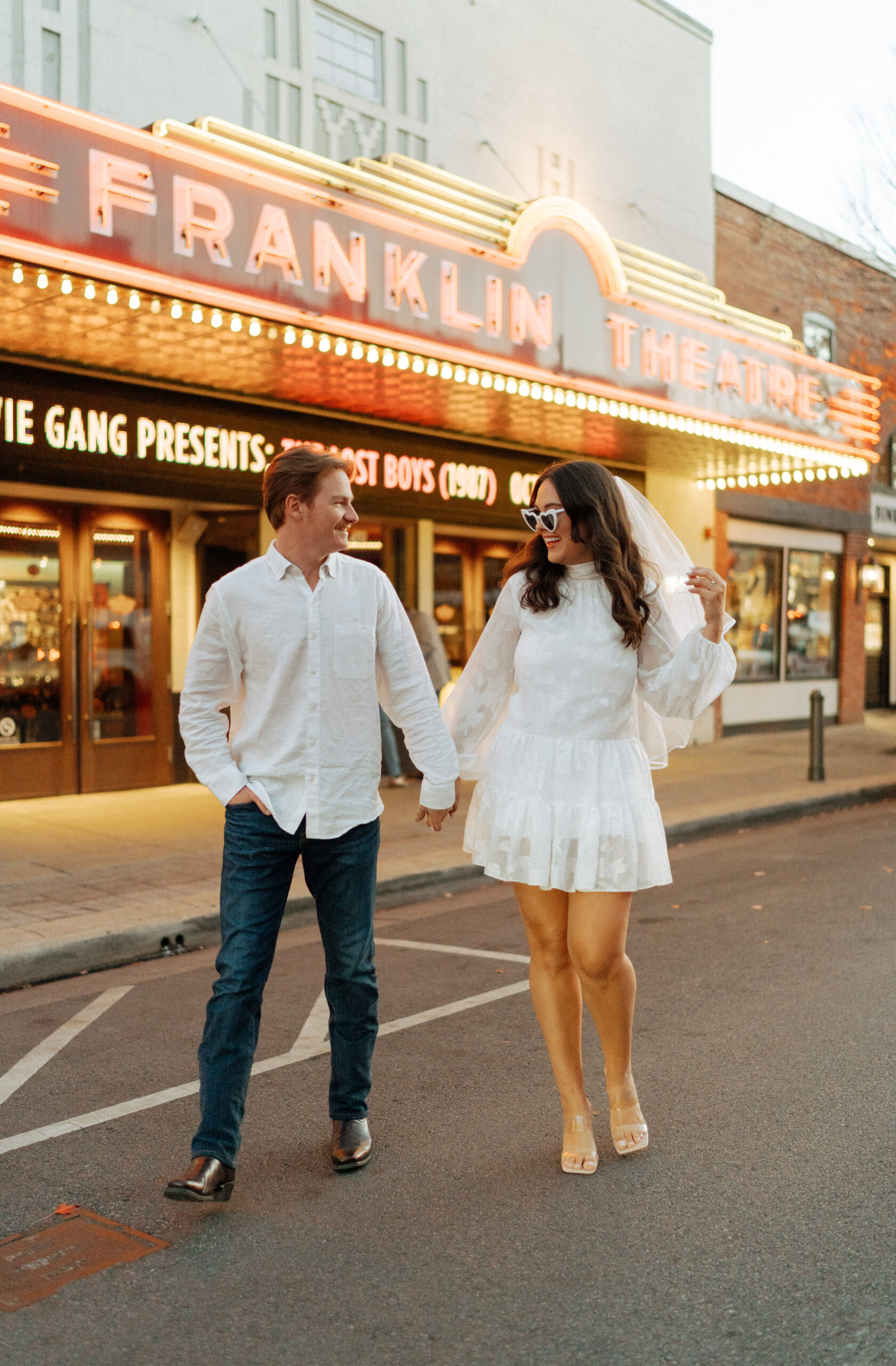 Couple taking photos in front of the Franklin Theatre during their engagement session