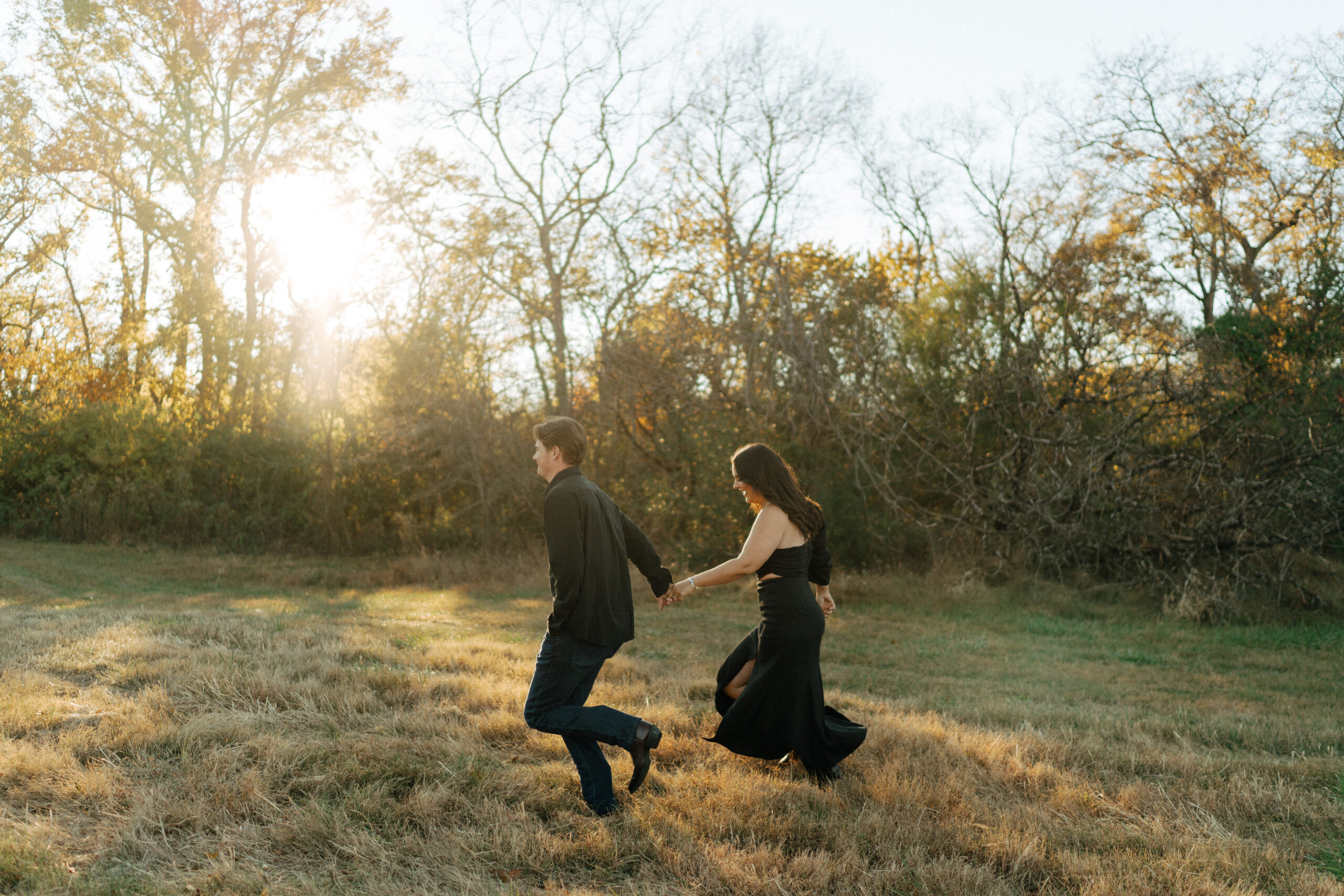 couple running through a field taking engagement photos in franklin tennessee