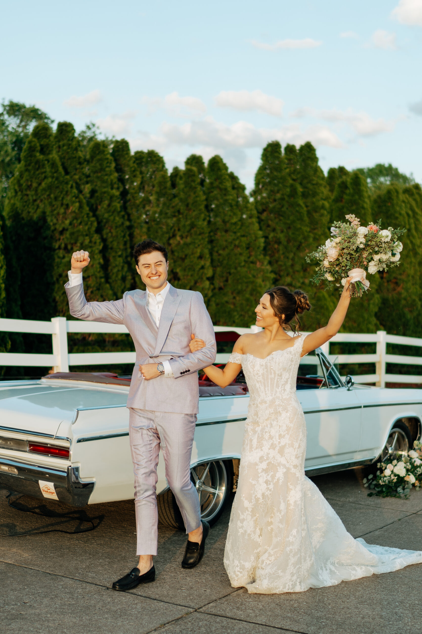couple posing in front of vintage car on their wedding day